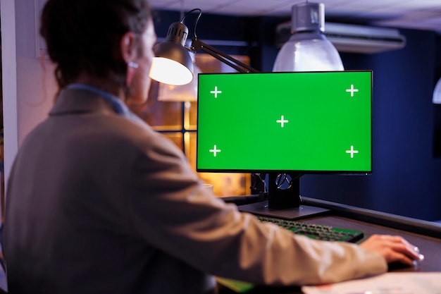 Исполнительный менеджер смотрит на зеленый экран, макетирует компьютер с цветным ключом, анализирует маркетинговый график, планирует стратегию компании. Молодой предприниматель, работающий допоздна в стартап-офисе.
