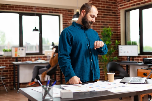 Executive manager waiting for business important call analyzing company strategy report working in startup office. Entrepreneur man looking at digital device before management meeting