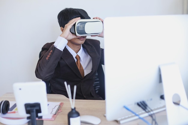 Executive staff in business suit using  virtual reality glasses in front of computer at the office