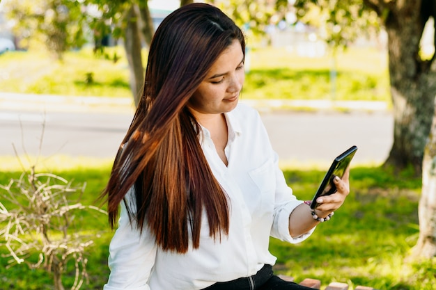 Исполнительная женщина с помощью своего телефона на скамейке в парке