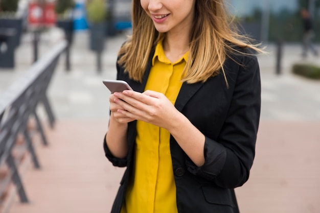 Executive working with a mobile phone in the street with office buildings in the background