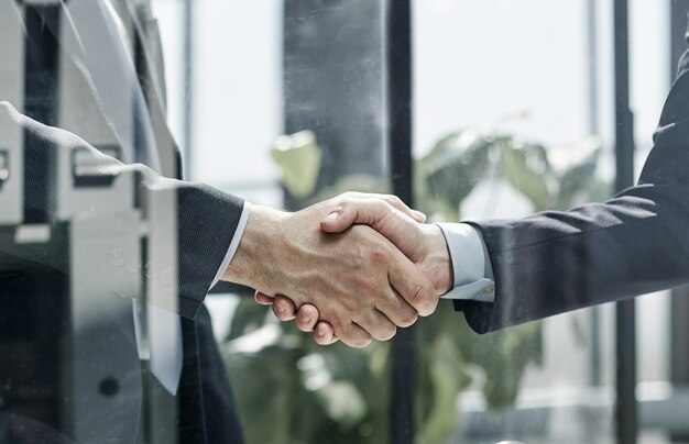 Executives shaking hands in front of their manager and a colleague