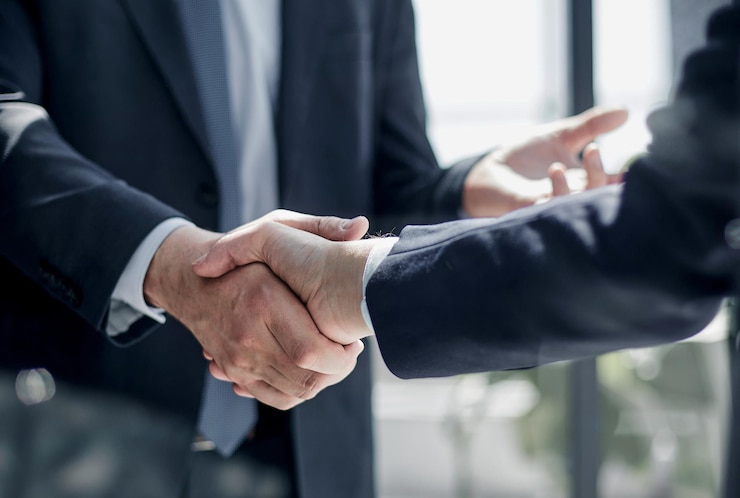 Photo executives shaking hands in front of their manager and a colleague