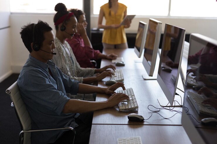 Photo executives working on personal computer while talking on headset in office