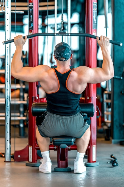 Упражнение на мышцы спины путем подтягивания шкива на силовом тренажере