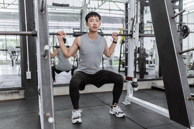 Photo exercise concept the strong guy playing weight machine by carrying the weight on his shoulder