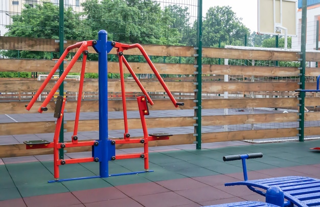 Exercise machines and fitness equipment for exercising on an open air sports ground in cloudy rainy weather without people.