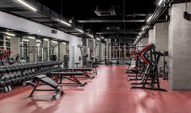 Exercise machines and racks with sets of black weights by the mirror in empty gym interior Special equipment for physical training Sport fitness