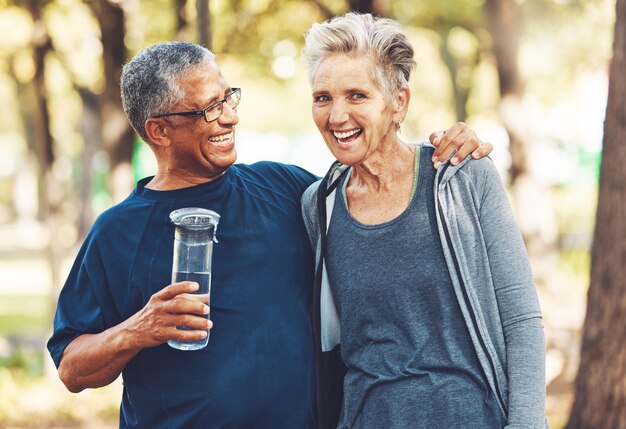 Exercise senior couple in park and water bottle for training workout and smile Mature man elderly woman and hydration for practice cardio and energy for wellness health and fitness in nature