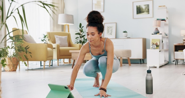 Foto esercizio yoga e tablet con fitness donna streaming online tutorial di classe o live stream su internet formazione virtuale in lounge a casa fit donna utilizzando la tecnologia per l'allenamento di benessere spirituale