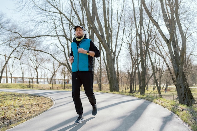 Esercitandosi all'aperto nel parco un atleta corre per le strade tra gli alberi