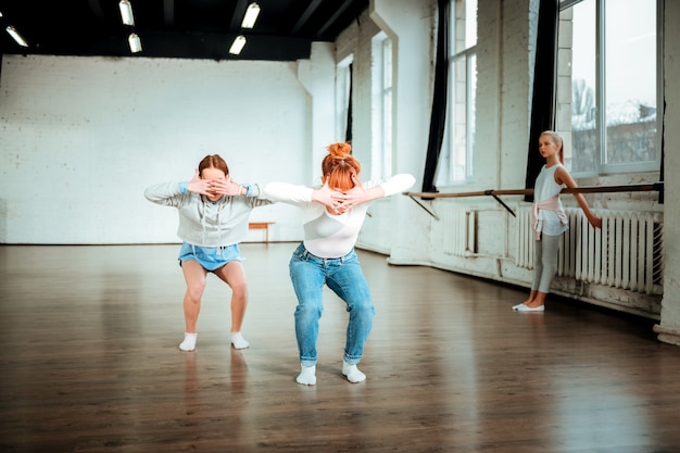 Exercising. Professional ballet teacher wearing blue jeans and her student exercising arm movements