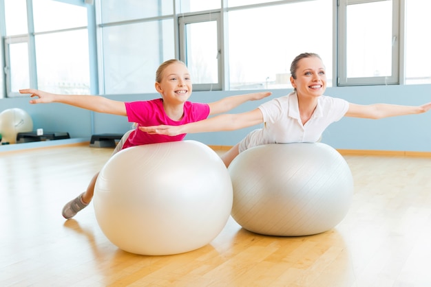 Esercitarsi con le palle fitness. madre e figlia allegre che si esercitano con le palle di fitness e sorridono