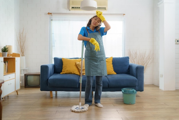 Exhausted Asian maid struggles with fatigue while mopping the house