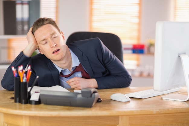 Exhausted businessman sleeping at his desk