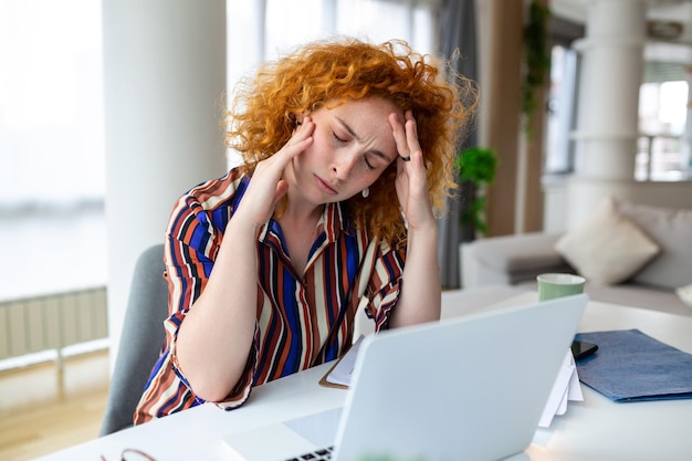 Foto donna di affari esausta che ha un mal di testa nel suo ufficio