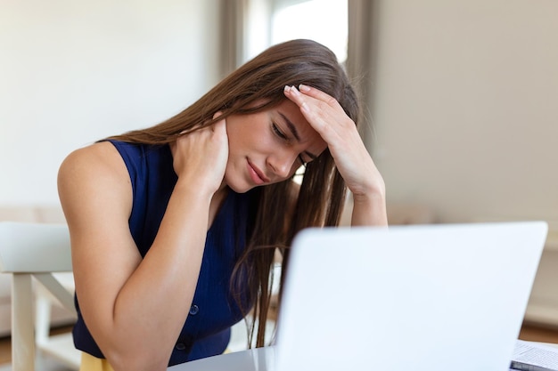 Exhausted businesswoman having a headache in home office creative woman working at office desk feeling tired