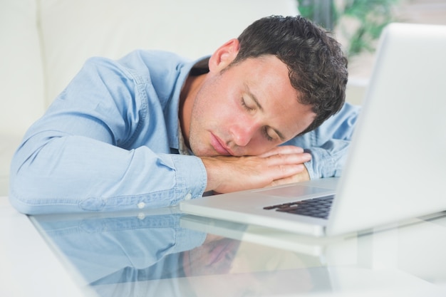 Exhausted casual man sleeping with head resting on table