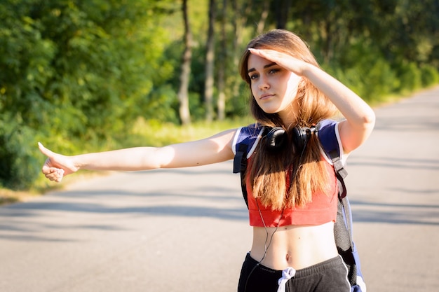 Exhausted girl looking for a car to pick her up