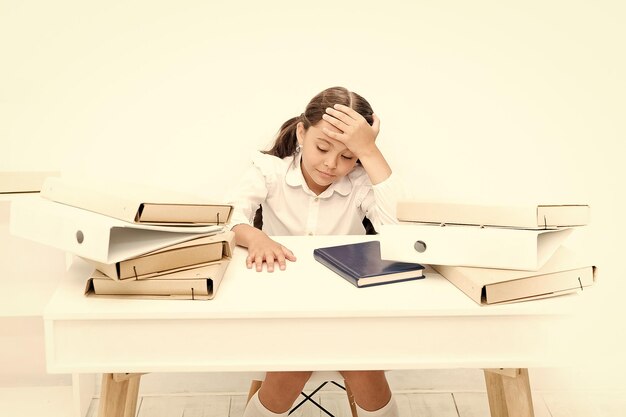 Exhausted girl with workbook and folders Education boring lesson Towards knowledge small girl on lesson homework and home schooling kid learn and study hard back to school tired and sleepy