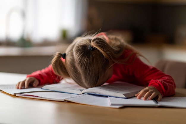 Photo exhausted little girl sleeping on books while doing school homework