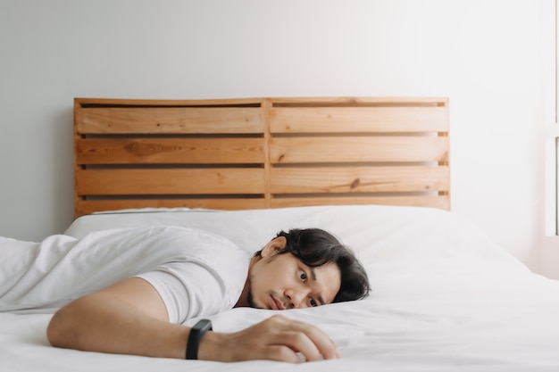 Exhausted man lay on the bed as he feels burnout