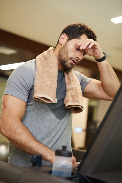 Photo exhausted man running on treadmill