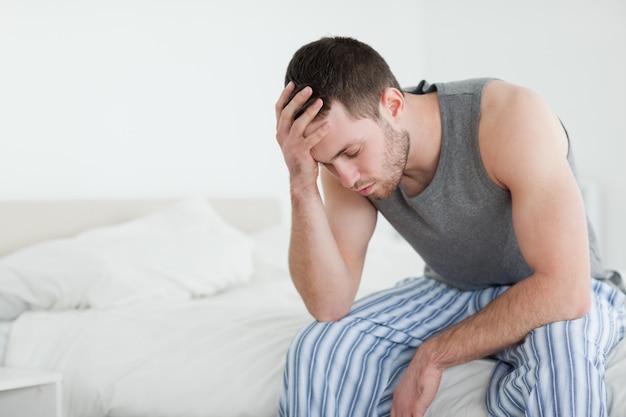 Exhausted man sitting on his bed