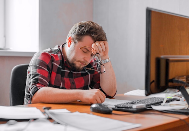 Exhausted man working in an office before the deadline. Close up photo