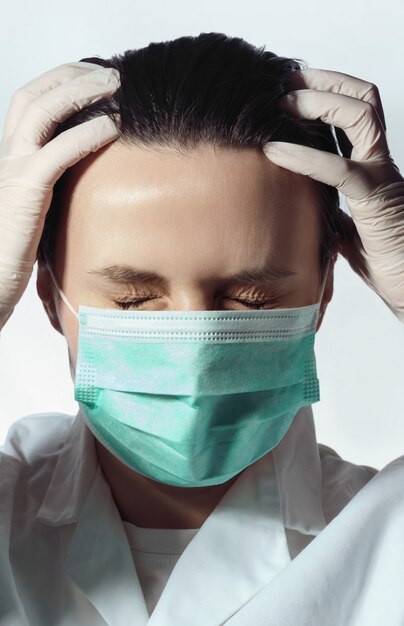 Exhausted medical worker touching head because of pain with closed eyes