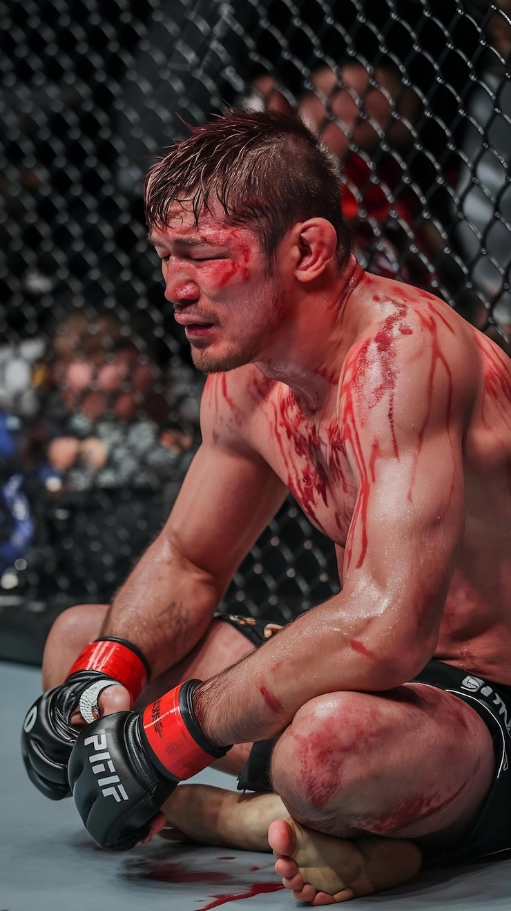 Photo exhausted mixed martial arts fighter sitting inside the octagon covered in blood and sweat restin
