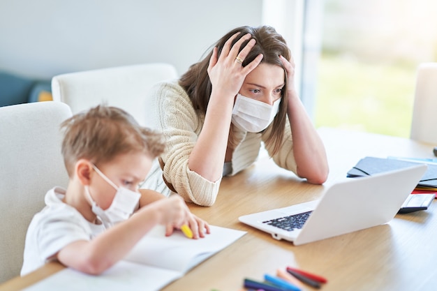 exhausted mother trying to work at home and taking care of her son during coronavirus pandemic