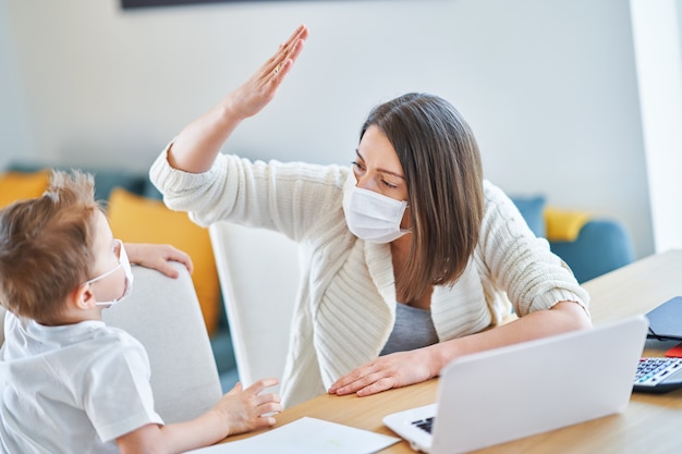 exhausted mother trying to work at home and taking care of her son during coronavirus pandemic