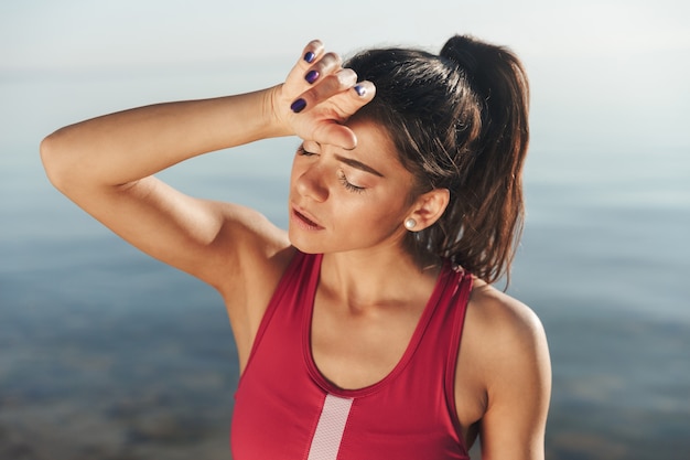 Photo exhausted sportswoman wiping her forehead after jogging