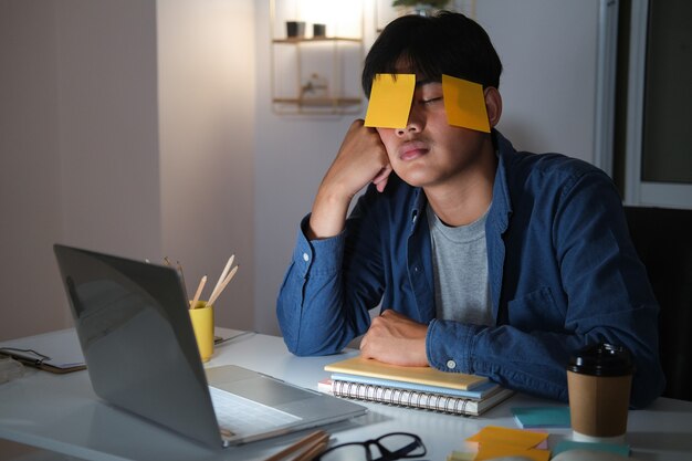 Exhausted tired workaholic young man with sticky note.