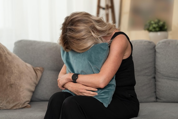 Exhausted woman crying and hiding her face in pillow