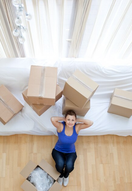 Exhausted woman sitting between boxes at home