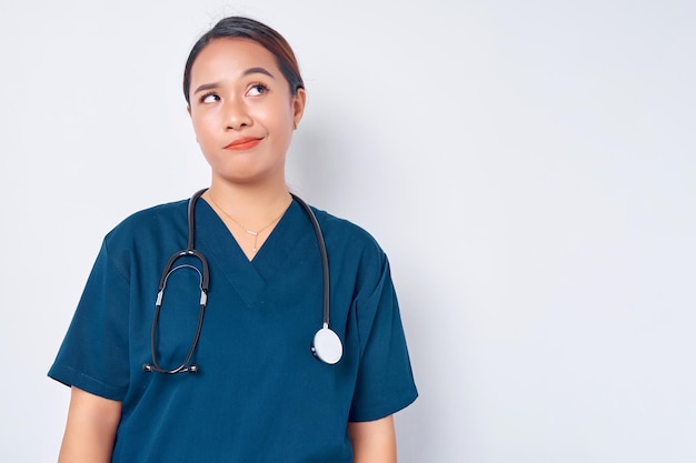 Exhausted young Asian woman nurse wearing blue uniform with a stethoscope looking tired after her shift in the hospital looking sad with fatigue on white background Healthcare medicine concept