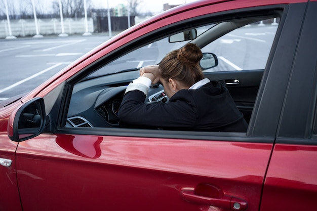 Exhausted young woman sleeping while driving a car