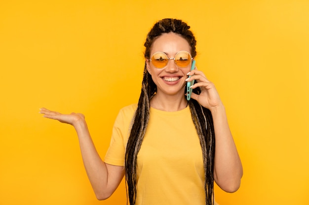 Exited woman talking phone on yellow wall.