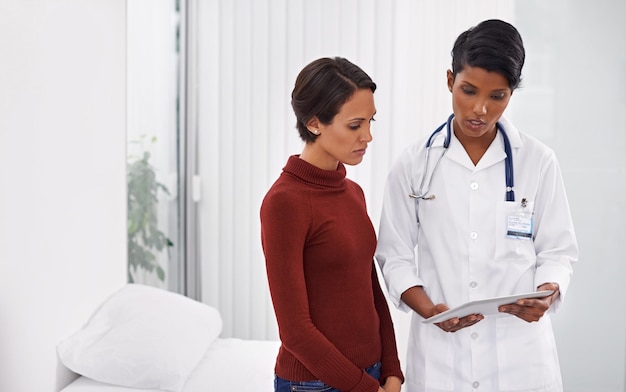 Exlpaining to alleviate the worry Shot of a female medical professional explaining a procedure to her patient using a tablet