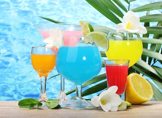 Exotic cocktails and flowers on table on blue sea background