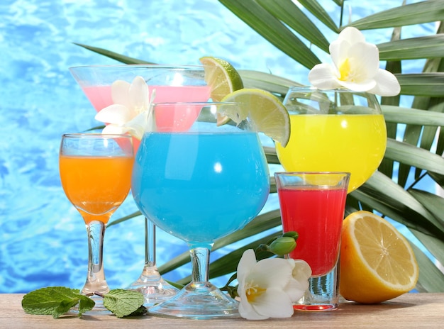 Photo exotic cocktails and flowers on table on blue sea background