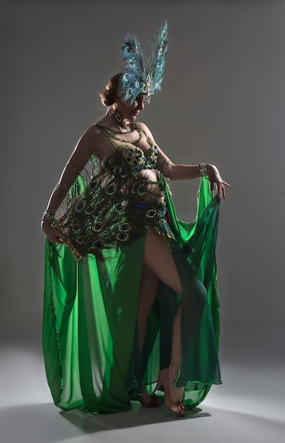 Exotic dancer in green costume with feathers