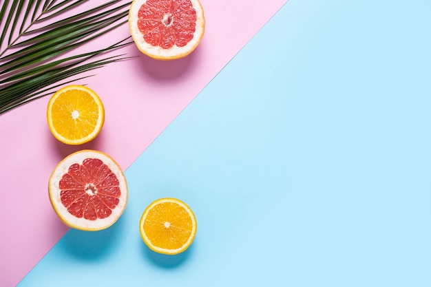 Photo exotic fruits on a blue pink background. coconut, orange, grapefruit.