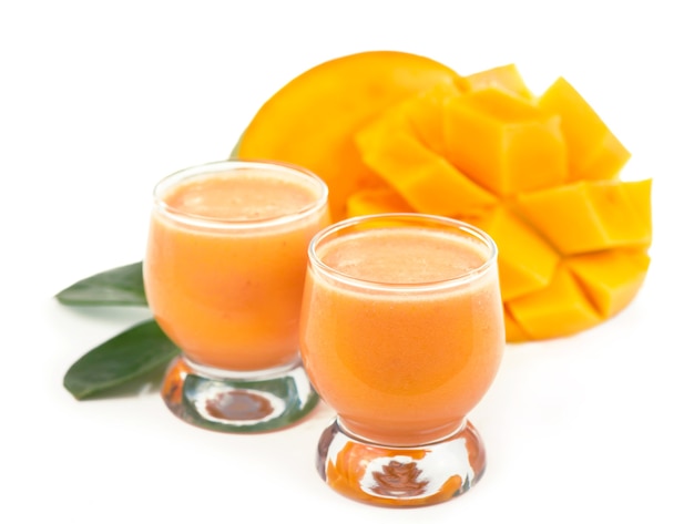 Frutti di mango succosi esotici e due bicchieri di succo di mango naturale fresco isolato su priorità bassa bianca