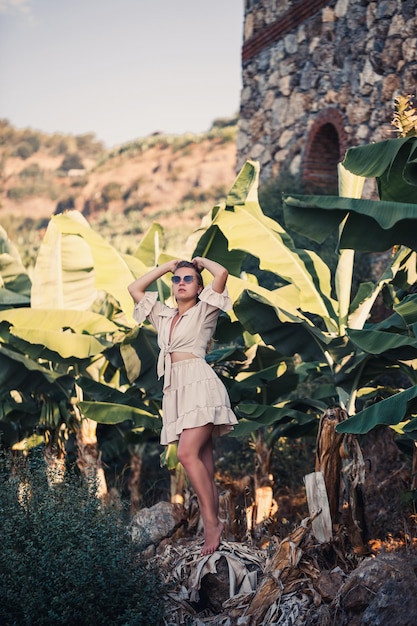 Exotic tropical woman near green leaves of banana bush Tropical island girl on vacation