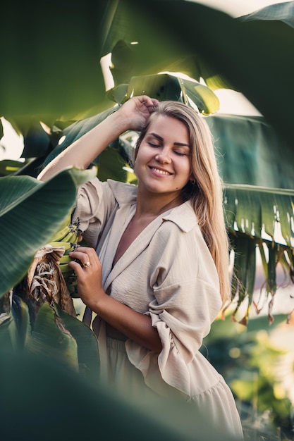 Exotic tropical woman near green leaves of banana bush Tropical island girl on vacation