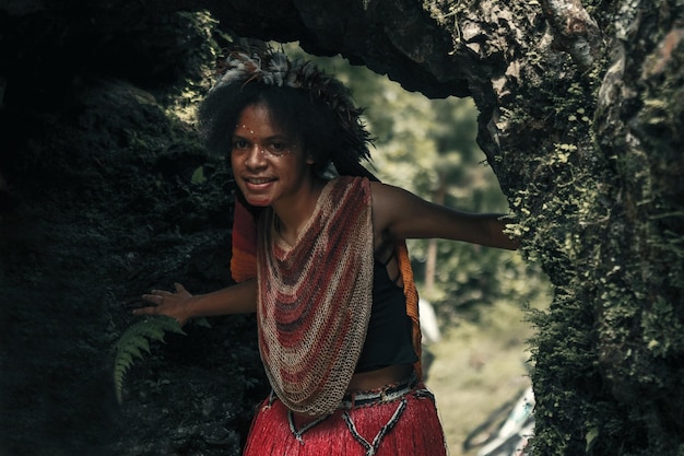 깃털 왕관을 쓴 전통 의상을 입은 다니 부족의 이국적인 젊은 파푸아 소녀가 웃고 놀고 있다