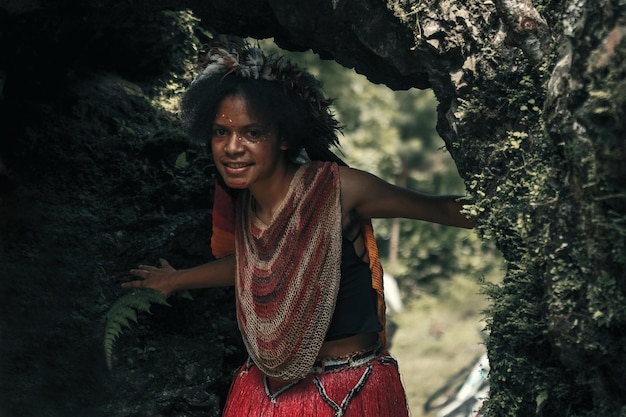 Exotic Young Papua girl of Dani tribe in traditional clothes with feathers crown is smiling and play